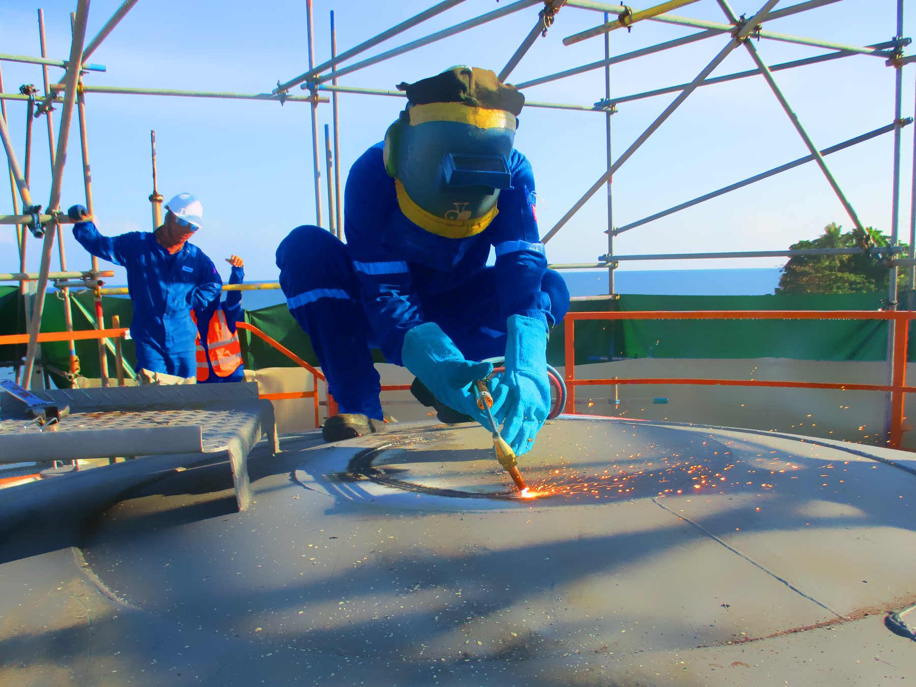 Hot work being carried out on a storage tank roof under scaffolding